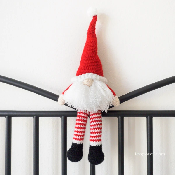 A crochet gnome toy dressed in a Santa outfit.