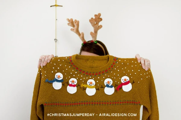 A mustard yellow jumper decorated with crochet snowmen.
