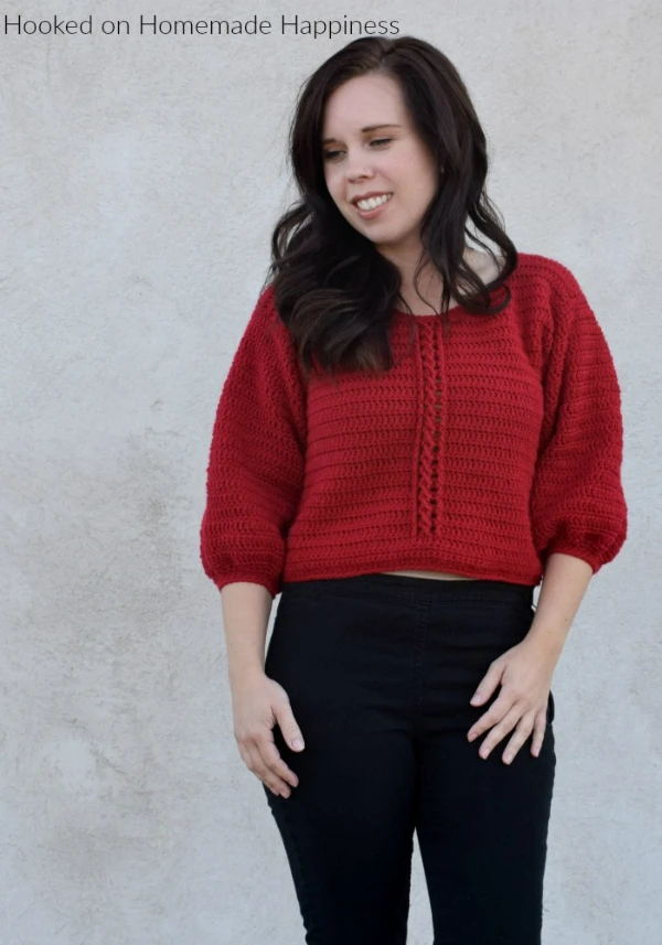 A red cropped crochet Christmas sweater with cable detail.