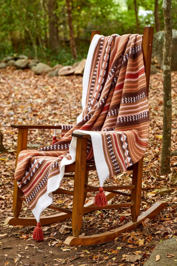 A tapetry c rochet blanket made in warm autumnal colours.