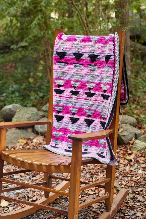 A brightly coloured tapestry crochet blanket with triangle motifs.