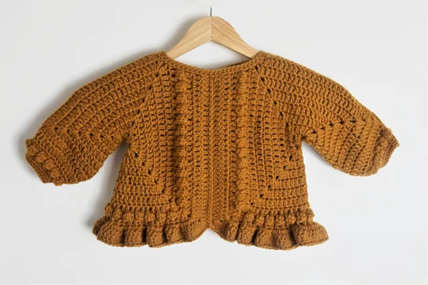 Granny square baby sweater with ruffled hem.