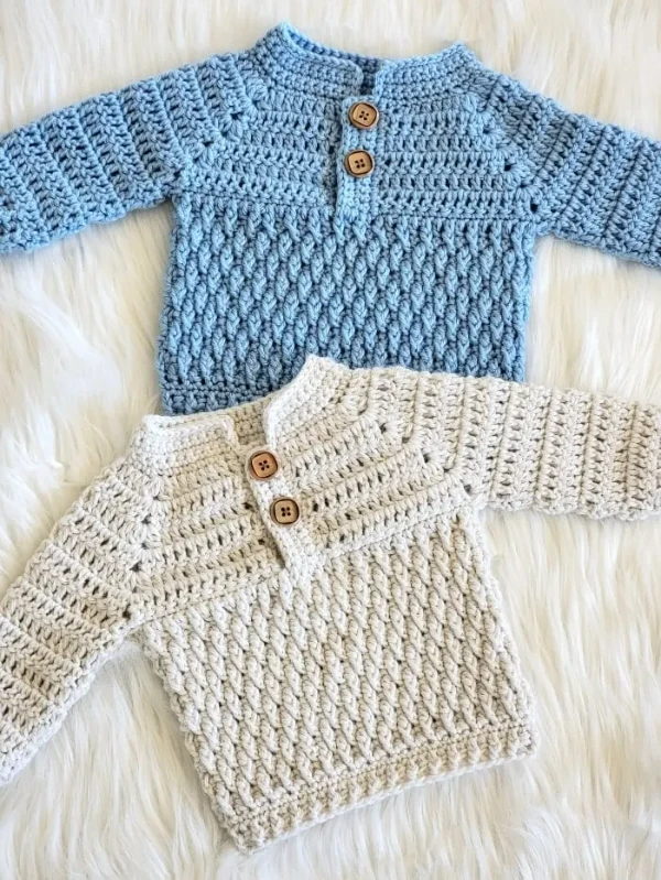 Two textured crochet baby sweaters with buttons.