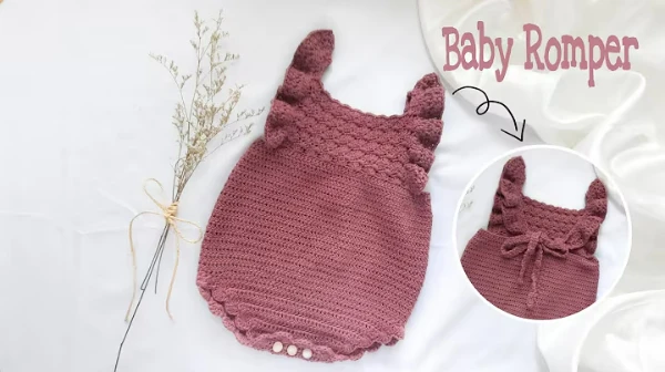 A dusky rose coloured crochet baby romper with ruffled straps.