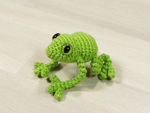 A green crochet tree frog toy.