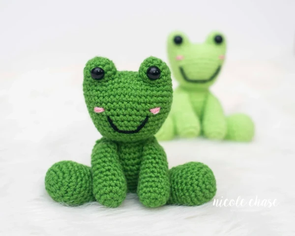 A sitting crochet frog plushie.