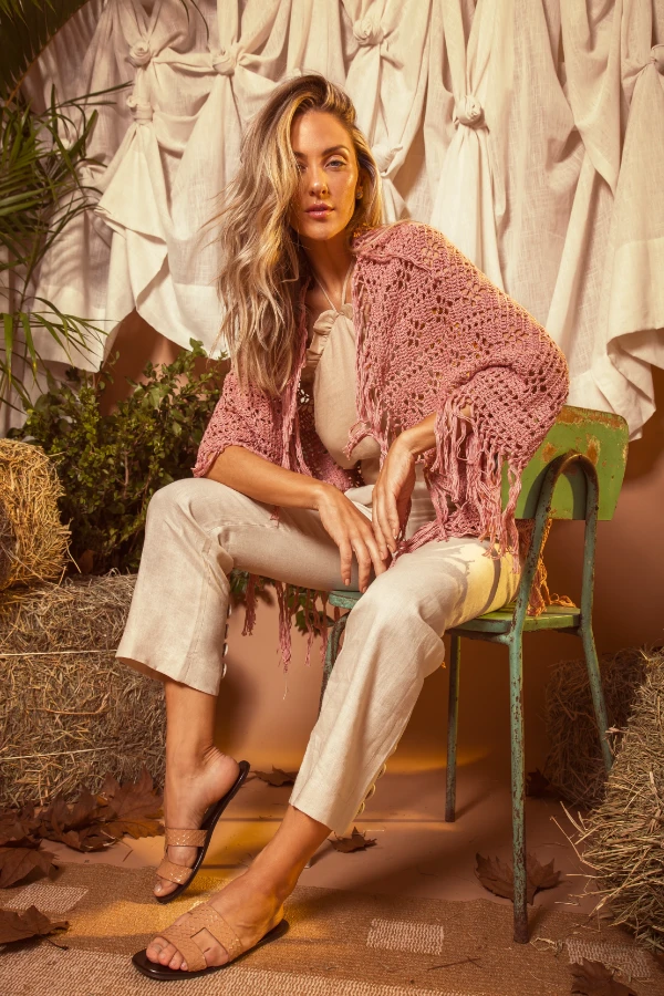 A woman wearing a boho-style crochet shrug with tassels.