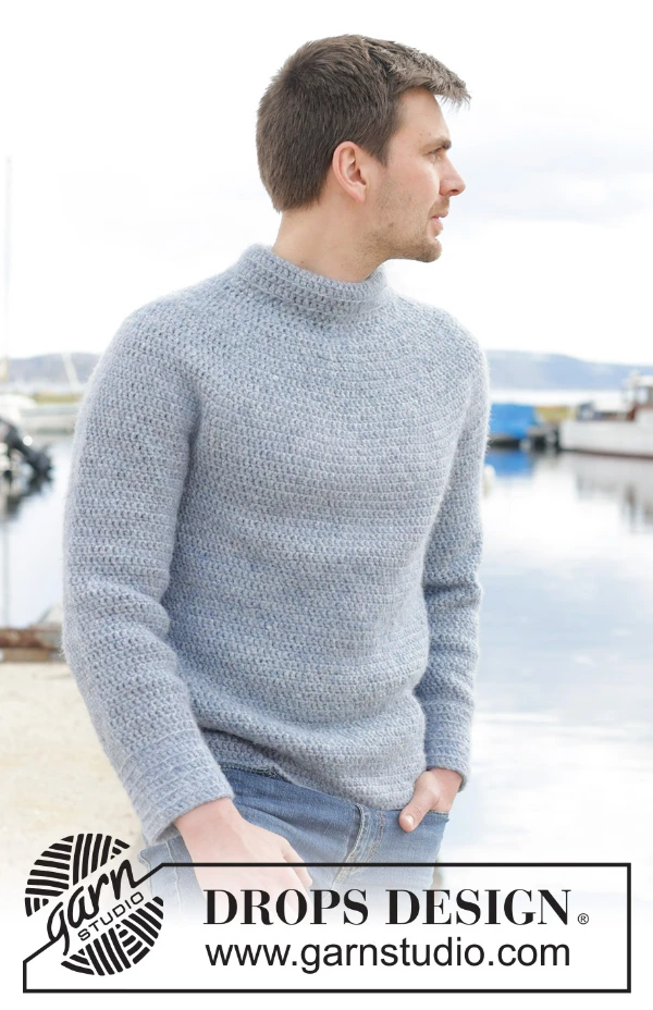 A man wearing a light grey crocheted sweater with a circular yoke.