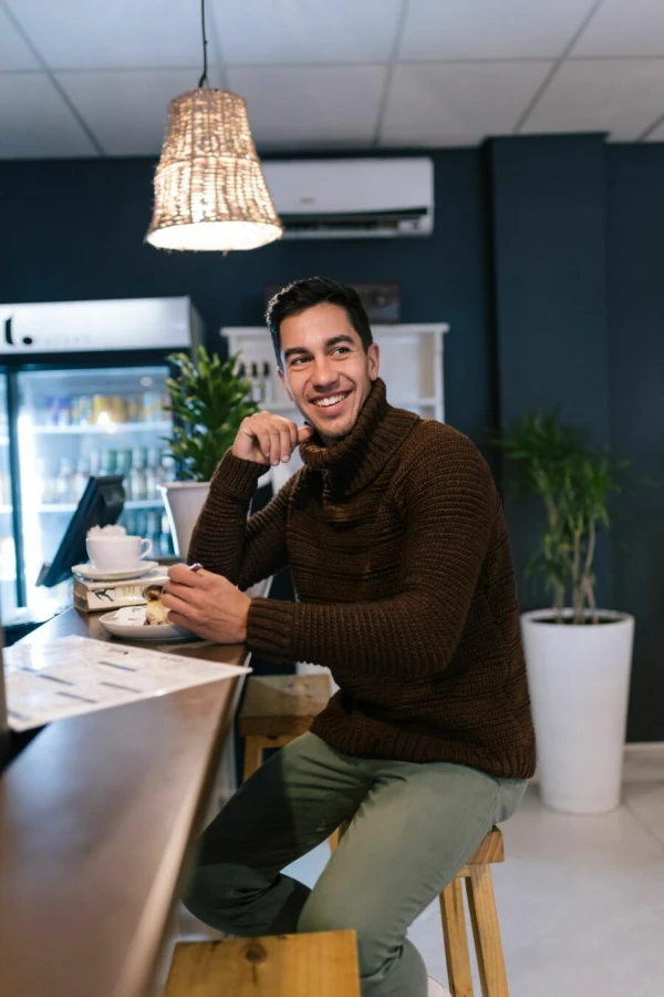 A man wearing a dark coloured crochet turtleneck sweater.