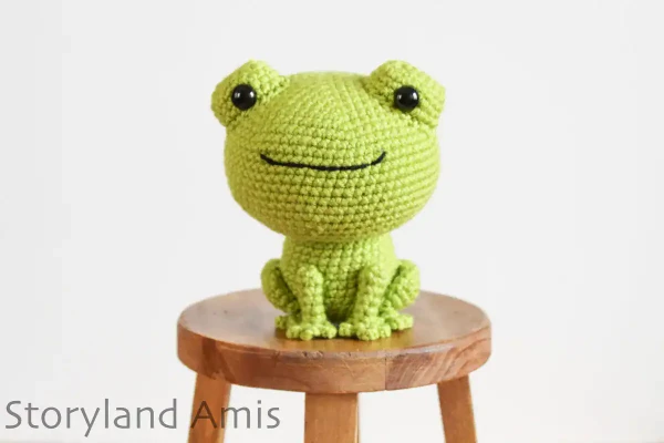 Crochet frog amigurumi with a big head.