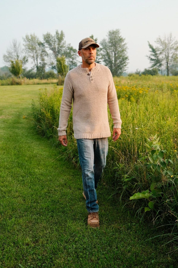 A man wearing a crocheted henly-style sweater with jeans.