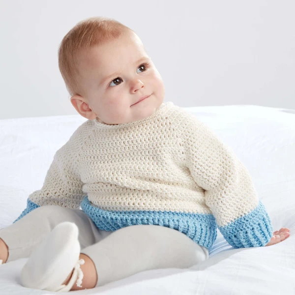 A baby wearing a colour-blocked crochet pullover.