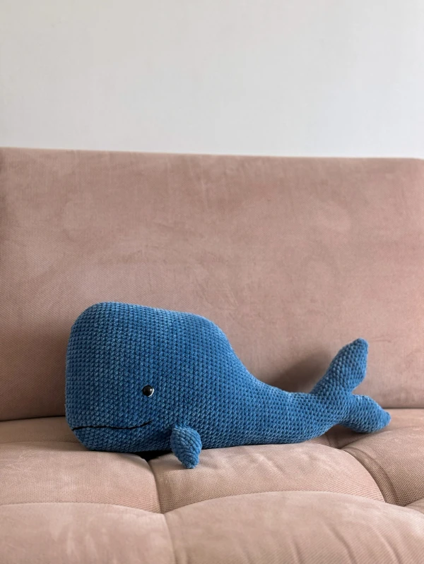A cartoon-style crochet sperm whale pillow.