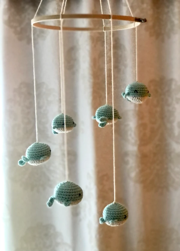 A crochet crib mobile featuring baby whales.