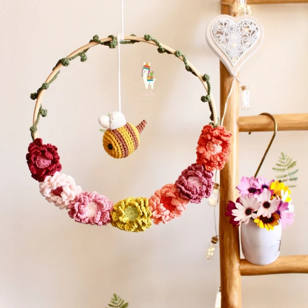 A flower garland styled mobile with a hanging bee.