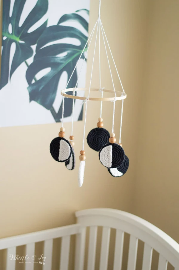 A black and white crib mobile with different phases of the moon represented.