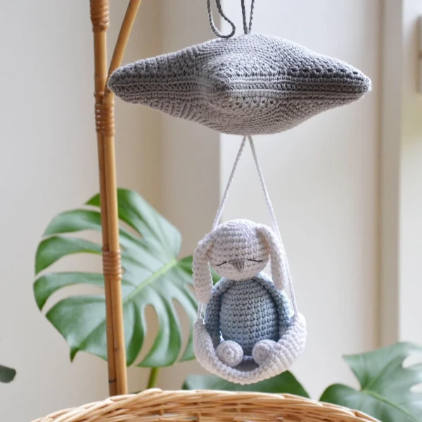A nursery mobile with a crochet bunny hanging from a star.