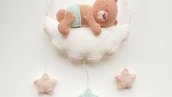 A crochet mobile featuring a baby bear sleeping on a cloud