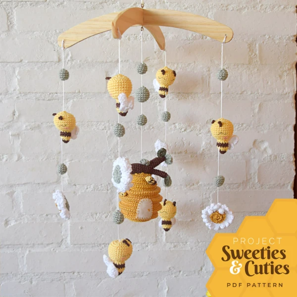 A crochet baby mobile with bees and a hive.