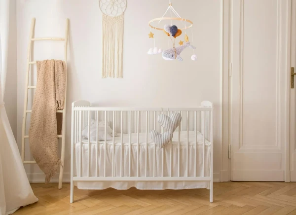 A crochet whale mobile hanging over a crib.