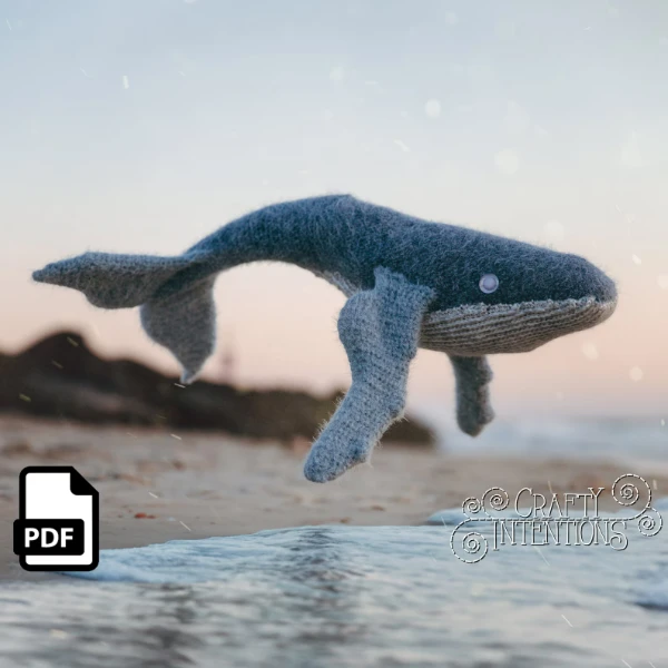 A large crochet whale with a beach background.