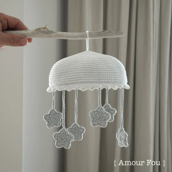 A grey and white crochet star themed mobile.