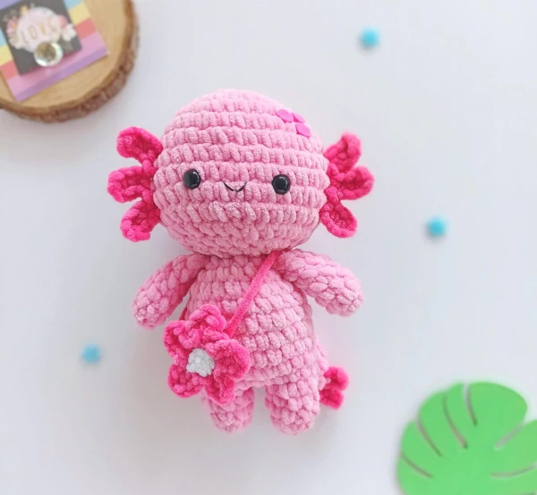 Bright pink crochet axolotl with flower bag.