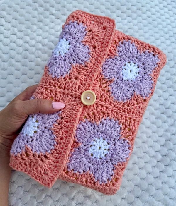 A crocheted book cover made from retro flower granny squares.