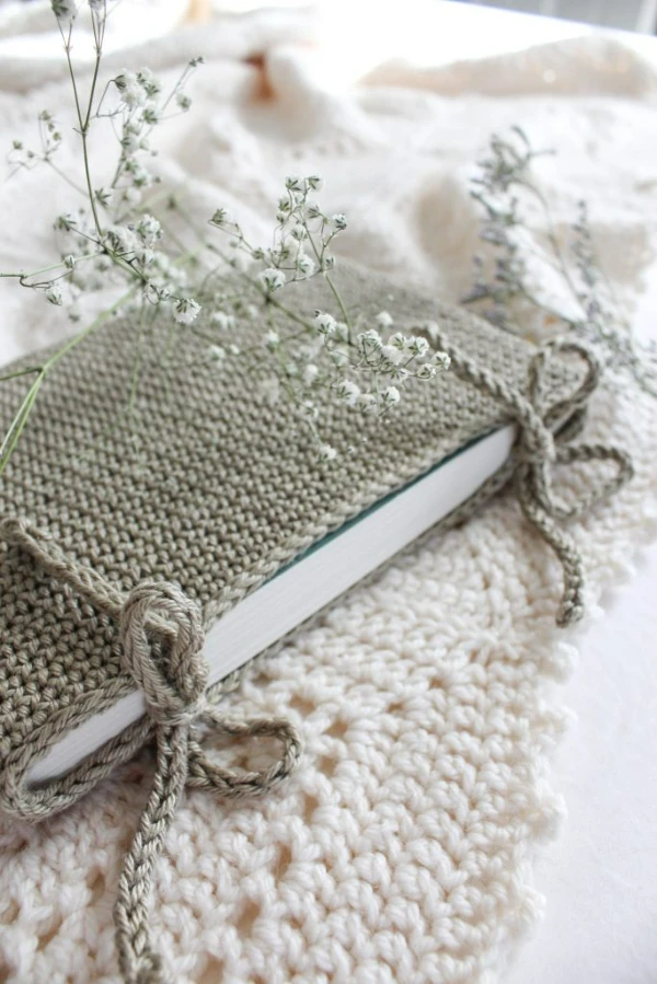 A book with a grey crochet cover with simple bow tie closures.