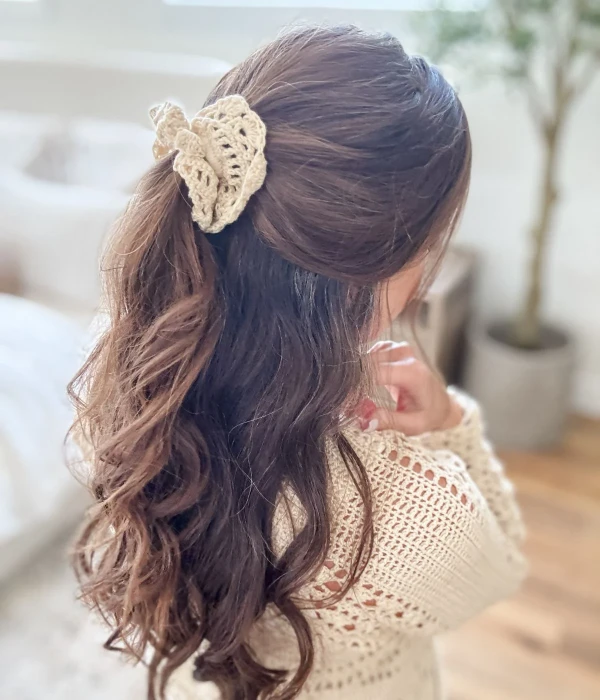 Woman wearing a cream coloured crochet scrunchie.
