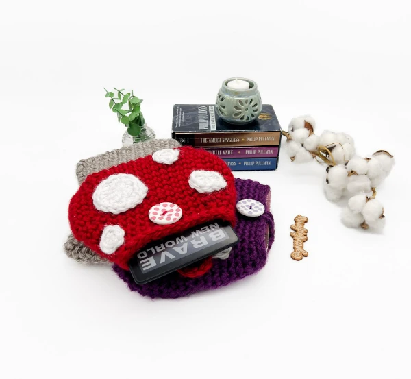 A crochet book sleeve in the shape of a mushroom.