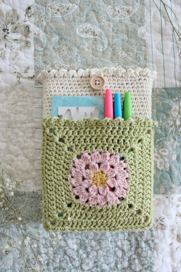 A crochet journal sleeve with a pocket for pens and accessories.