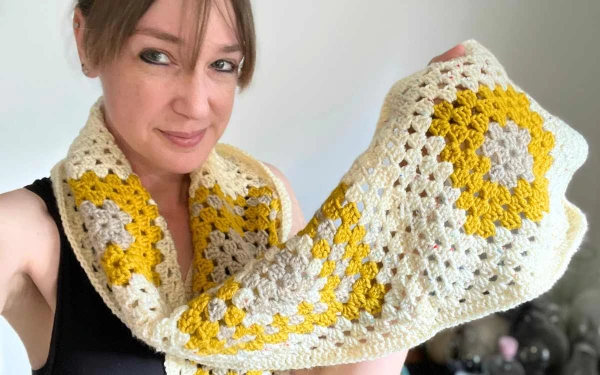 A yellow and white crochet scarf made from large granny squares.