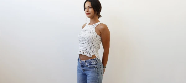 Woman wearing a crochet tank top and jeans.