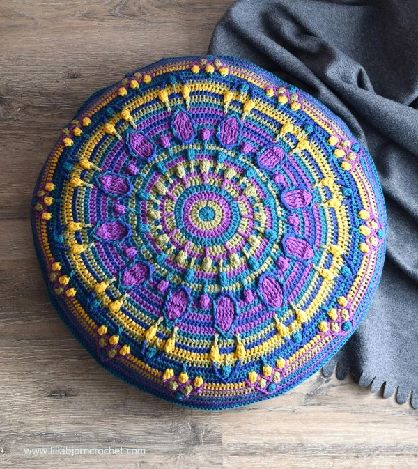 An intricate, colourful mandala round crochet floor pillow.