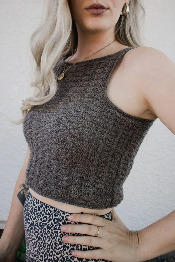 Woman wearing a crochet tank top with a high neckline.