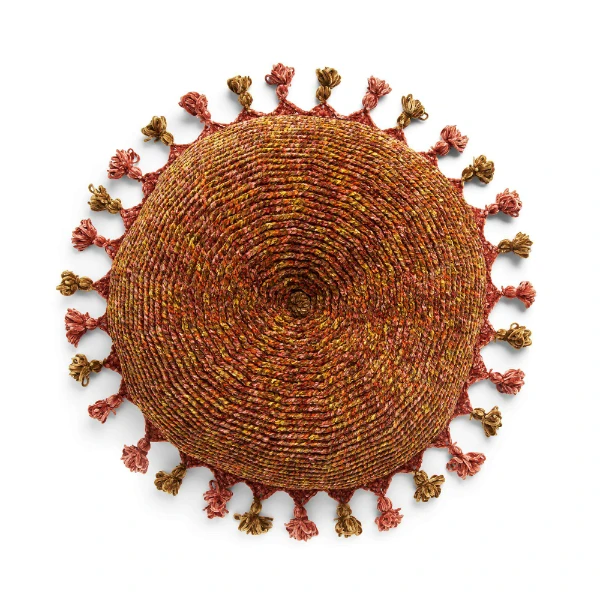A round crochet floor pillow with tassels.
