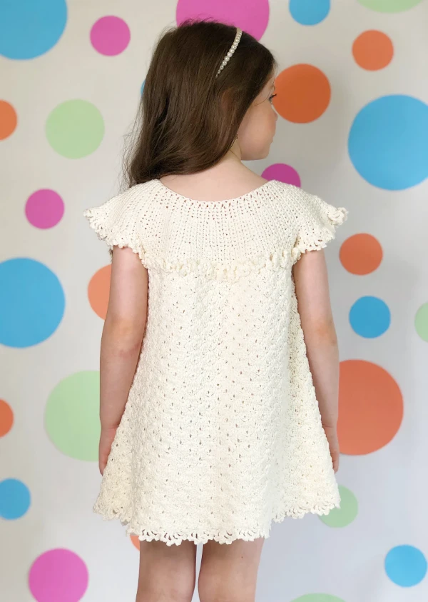 A small girl wearing a white crochet dress.