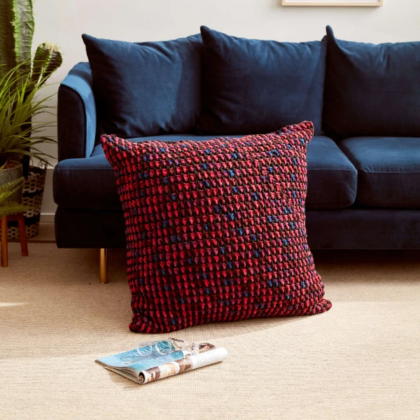 A large crochet floor pillow next to a sofa.