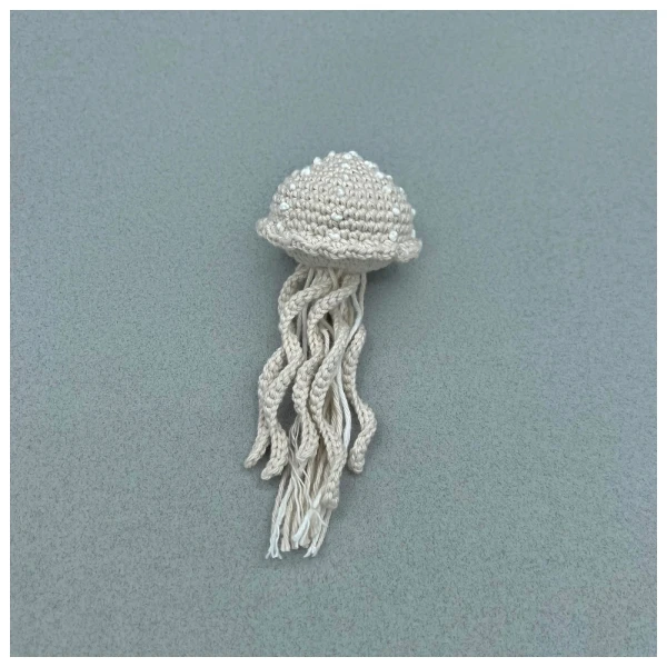 A beige coloured jellyfish with white embroidery.