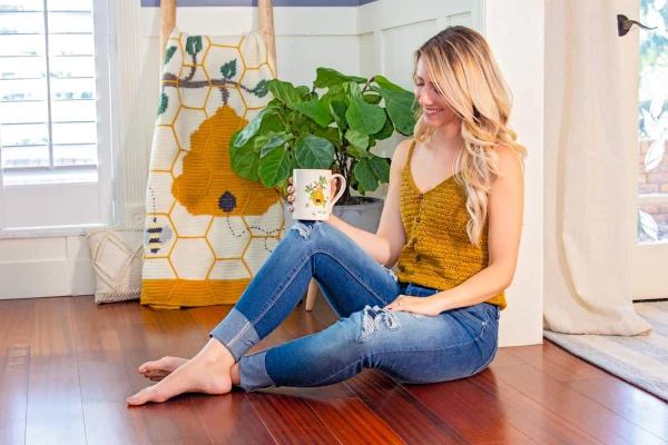 Woman wearing a mustard coloured crochet tank top with a button front.