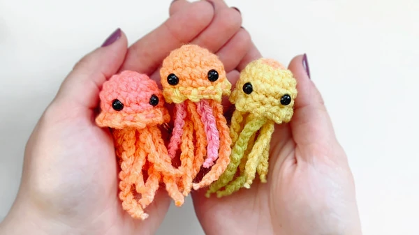 Three miniature jellyfish amigurumi in a pair of hands.