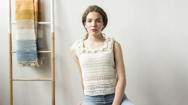 A woman wearing a crochet tank top with a ruffle neckline.