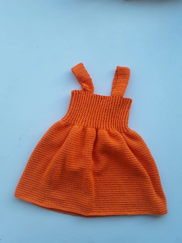 A bright orange crochet baby dress with rib sttich bodice.