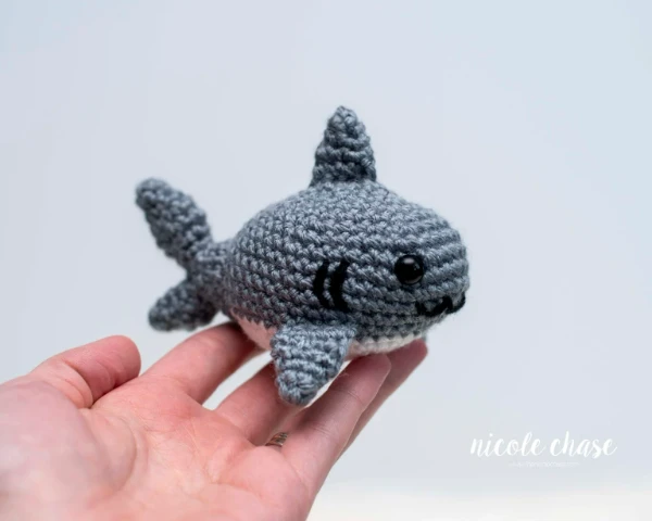 A crochet shark sittingin an open hand.