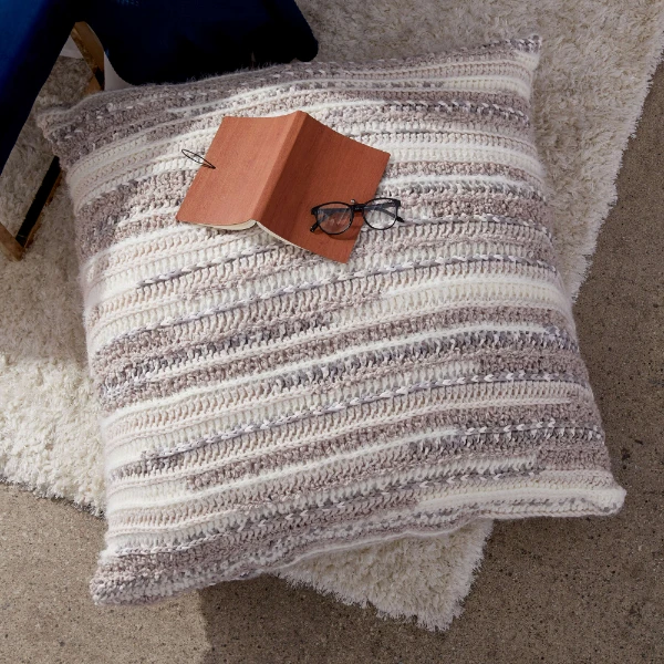 A large crochet floor pillow and a book.