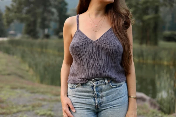 A woman wearing a grey coloured crochet tank top.