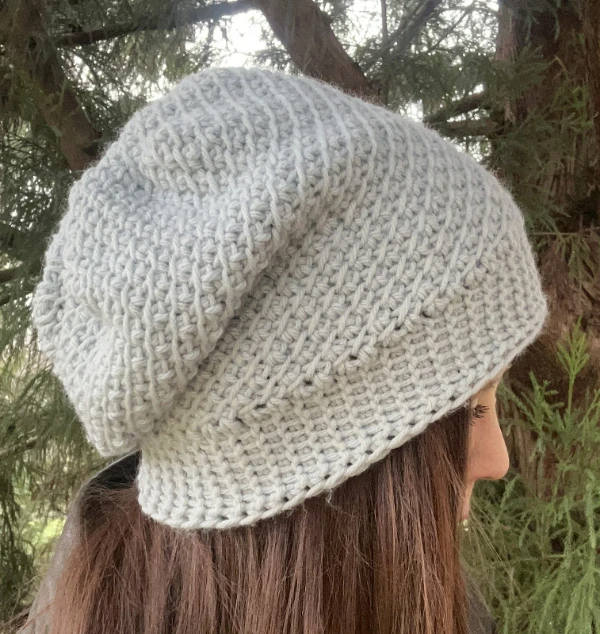 A side view of a woman wearing a slouchy Tunisian crochet hat.
