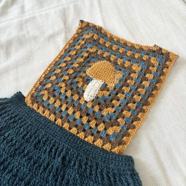 A pinafore-style crochet children's dress with a mushroom motif.