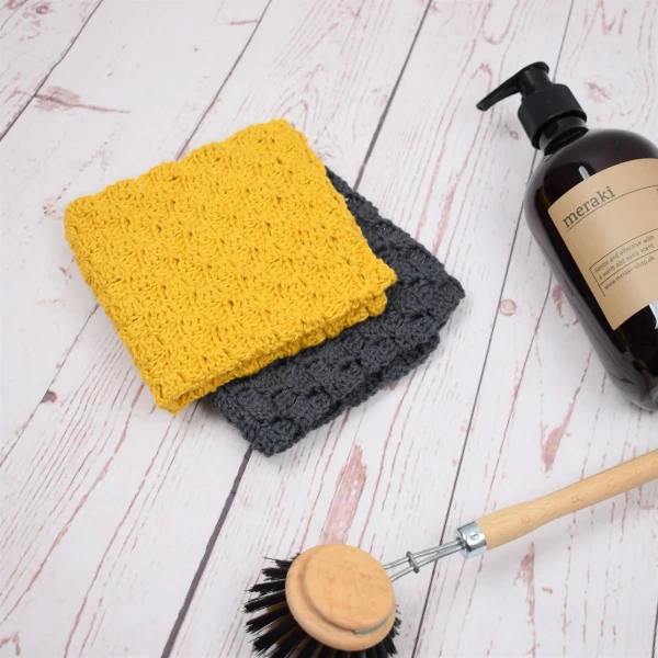 A bright yellow and a charcoal grey c2c crochet dishcloths.